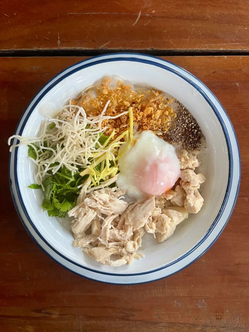 A bowl with chicken, egg, ginger, and fresh greens.